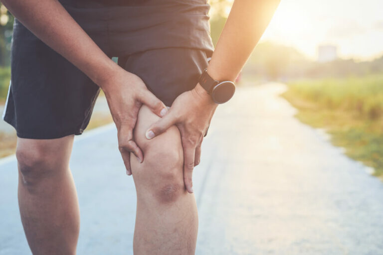 Person in exercise clothes holding their knew in pain