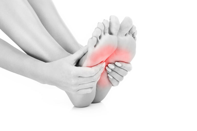 A person holding both of their feet, with pain radiating from the bottom of the feet