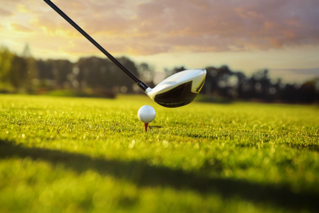 Closeup of golf club being held above a ball on a tee