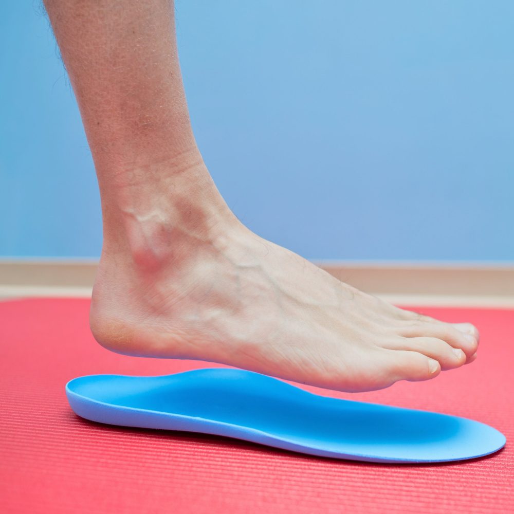 A foot is held above an orthotic insert